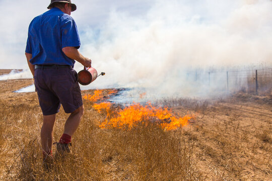 Farmer carrying a fire lighter burning grass