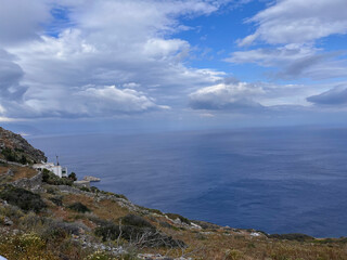Coastal hillside with dramatic cloudscape and deep blue sea on Amorgos Island, Greece – wild Mediterranean vegetation and scenic Aegean view