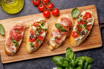 Tasty antipasto toasts featuring classic caprese with mozzarella and tomatoes, and savory prosciutto with herbs