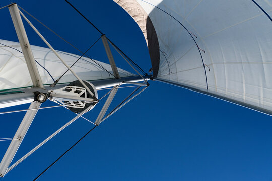 open sails on mast, view from bottom of sail boat, lighting rods, search light, deep blue sky