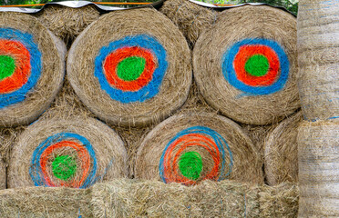 group of round archery targets made from tightly packed hay bales, each painted with vibrant...