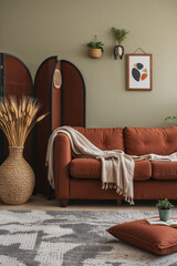 A cozy living room scene, showcasing a blend of modern and bohemian styles. The walls are painted in a muted olive green, providing a neutral backdrop for the room's decor
