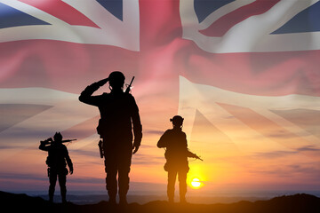 Silhouettes of a soldiers with United Kingdom flag against the sunset. Background for Remembrance...