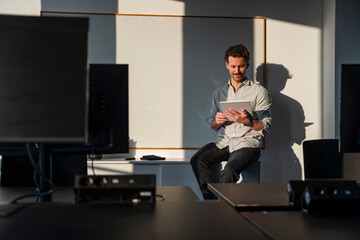 Man in office using tablet during sunset