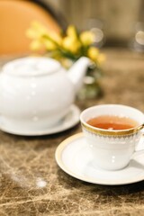 Close-up of a fine bone china teacup with gold trim and a pot of Taiwanese tie guan yin oolong tea at the lounge of Montien Surawong, a hotel in Silom - Bang Rak, Bangkok, Thailand