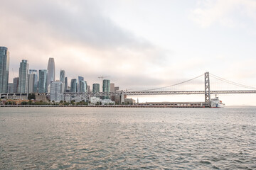 Fototapeta premium Skyline of San Francisco viewed from across the bay with Bay Bridge angled to the right and low cloud cover – San Francisco, CA on May 11, 2019