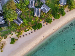 A row of resort villas lines the coast of Le Morne, Mauritius beside a turquoise lagoon and coral reef