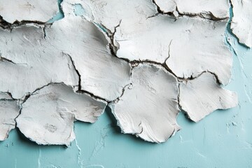 Close-up view of cracked white material on a light teal background.