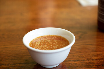 A close-up of a traditional Japanese miso soup served in a white bowl on a wooden table, showcasing its texture and warmth, captured May 27, 2019