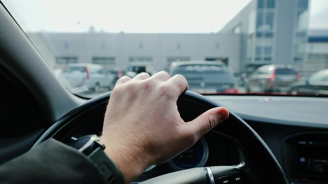 Hand on steering wheel waiting stressed at Latvian technical inspection station parking lot