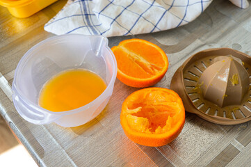 Fresh orange halves with juicer and bowl on kitchen table. Preparing homemade juice, healthy...