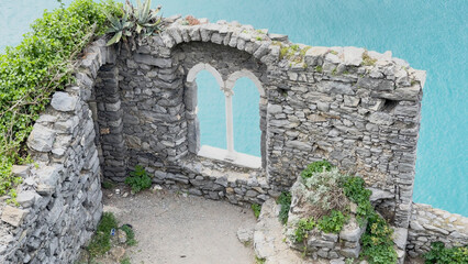 Stone medieval window of ruined building, Porto Venere. Sea among mountains, rocks in Italy, Liguria. 