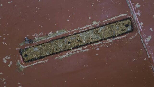 Zinc anode flush with ship hull appears worn and dirty during inspection in drydock. Anti corrosion use.