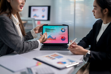 Two women are looking at a computer screen with graphs and charts