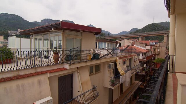View of rooftops in Letojanni, Sicily, with mountainous backdrop, and scenic coastline