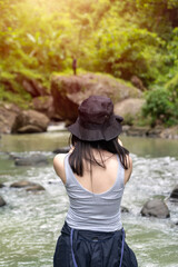 Asian Woman Exploring Nature by River with Bucket Hat Seen from Behind