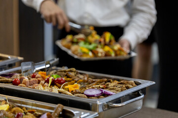 Guests enjoy a variety of grilled meats and vegetables at a buffet during a lively evening gathering in an elegant venue