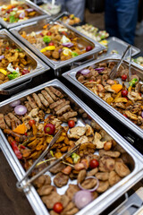 Various dishes displayed at a buffet featuring grilled meats, roasted vegetables, and garnishes during a festive event