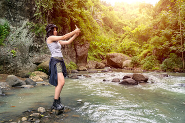 Young Asian Woman Taking Selfie in Forest Stream with Bucket Hat and Hiking Outfit