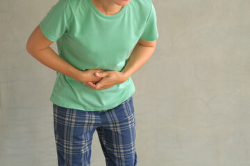Asian woman standing with severe stomach pain. Diarrhea. Emergency illness that requires...