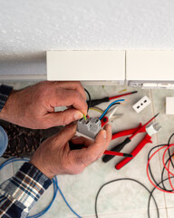 Electrician worker inserts electrical cables into the socket terminals of an electrical system. Construction industry.
