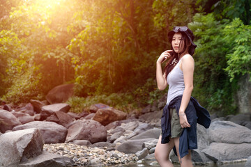 Smiling Asian Woman in Sunhat Looking Back in Lush Green Forest with Sunlight