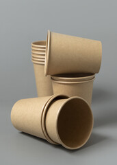Disposable beige kraft paper cups on a gray closeup, mockup. No plastic and sustainable lifestyle