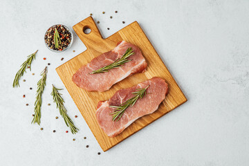 Fresh pork chops ready for cooking with herbs and spices on a wooden board