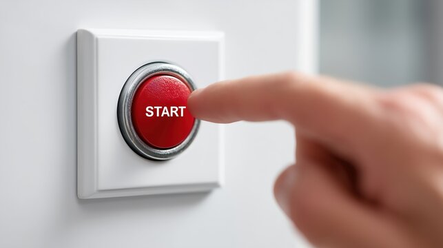 A finger pressing a red start button mounted on a wall plate, symbolizing initiation, power, and beginning of process or system