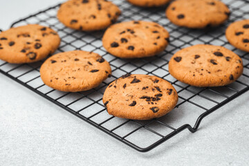 Freshly baked chocolate chip cookies cooling on a wire rack in a kitchen