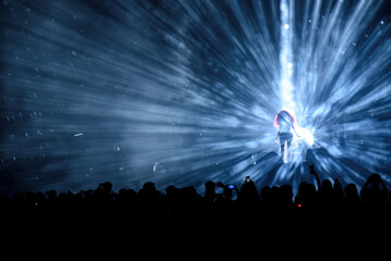 Music festival. The singer shines in the stage lights, surrounded by the audience.