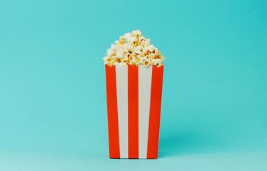 Popcorn in a red and white striped container against a blue background