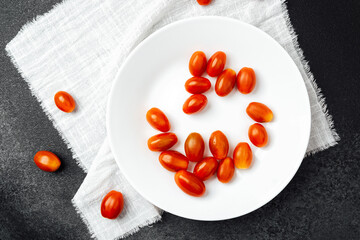 Fresh cherry tomatoes arranged on a white plate with a textured napkin