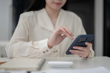 Close up of a female office worker hand hovering over phone while sitting at working table in office