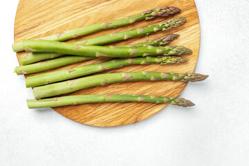 Fresh green asparagus arranged on a wooden cutting board in a kitchen setting