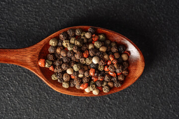 Variety of spices displayed on a wooden spoon on a dark background