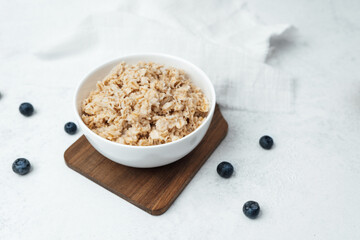 Healthy oatmeal served in a white bowl with fresh blueberries nearby