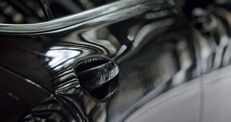 A close-up shot capturing the sleek and reflective surface of a luxury car. Ideal for conveying themes of elegance and high-end automotive design. Luxury Car Reflective Black Surface