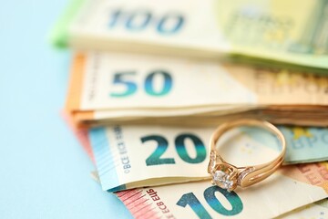 European union Euro money bills and coins with golden wedding ring on blue table