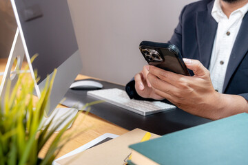 Fototapeta premium Partial view of a focused businessman multitasking, holding a phone to his ear while typing on a computer keyboard
