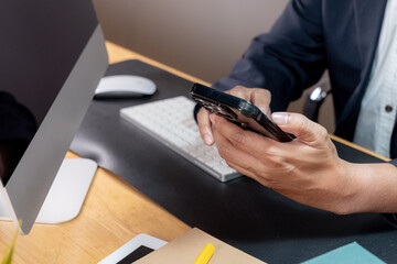 Partial view of a focused businessman multitasking, holding a phone to his ear while typing on a computer keyboard