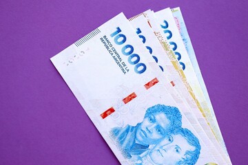 Argentine pesos money bills in big amount lies on purple color table close up