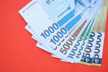 South Korean won money bills in big amount lies on red color table close up