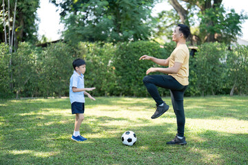 Wellness in Family Interaction: Father and son practicing soccer outdoors