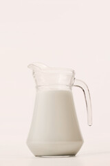 Minimal image of transparent pitcher filled with milk against clean white backdrop. Concept of drink, organic food, aesthetics, advertisement