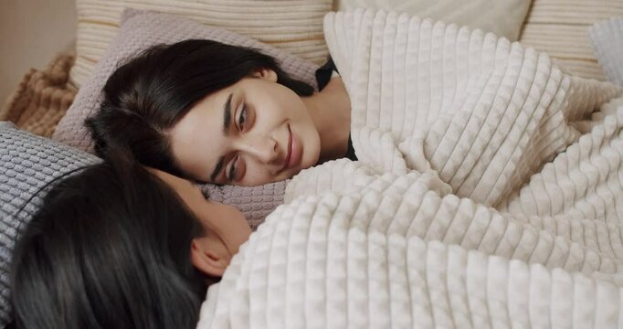 Couple of women hug each other warmly and relax at home in the bedroom. Lgbt and lesbian women at home. Embrace and holding each other. Romance and portrait of lesbian couple enjoying. LGBT rights.