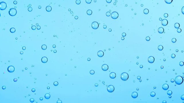 Blue foaming soap and bubbles of washing cleanser close up. Hyaluronic acid liquid makeup remover micellar water facial skin care. Powder foam close up background. Transparent cleaner. Shampoo texture