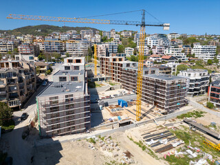 Modern residential buildings under construction with scaffolding and cranes, captured on a clear sunny day
