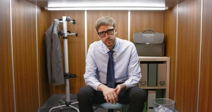 Sad frustrated businessman sitting in a small office