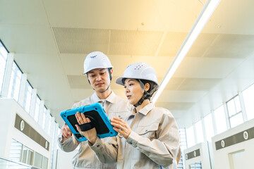 タブレットPCを見ながらビルの室内を点検する男女エンジニア